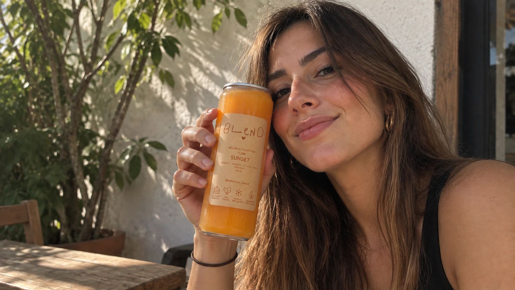 Una mujer sonríe al sol con una lata de Sunset junto a la cara
